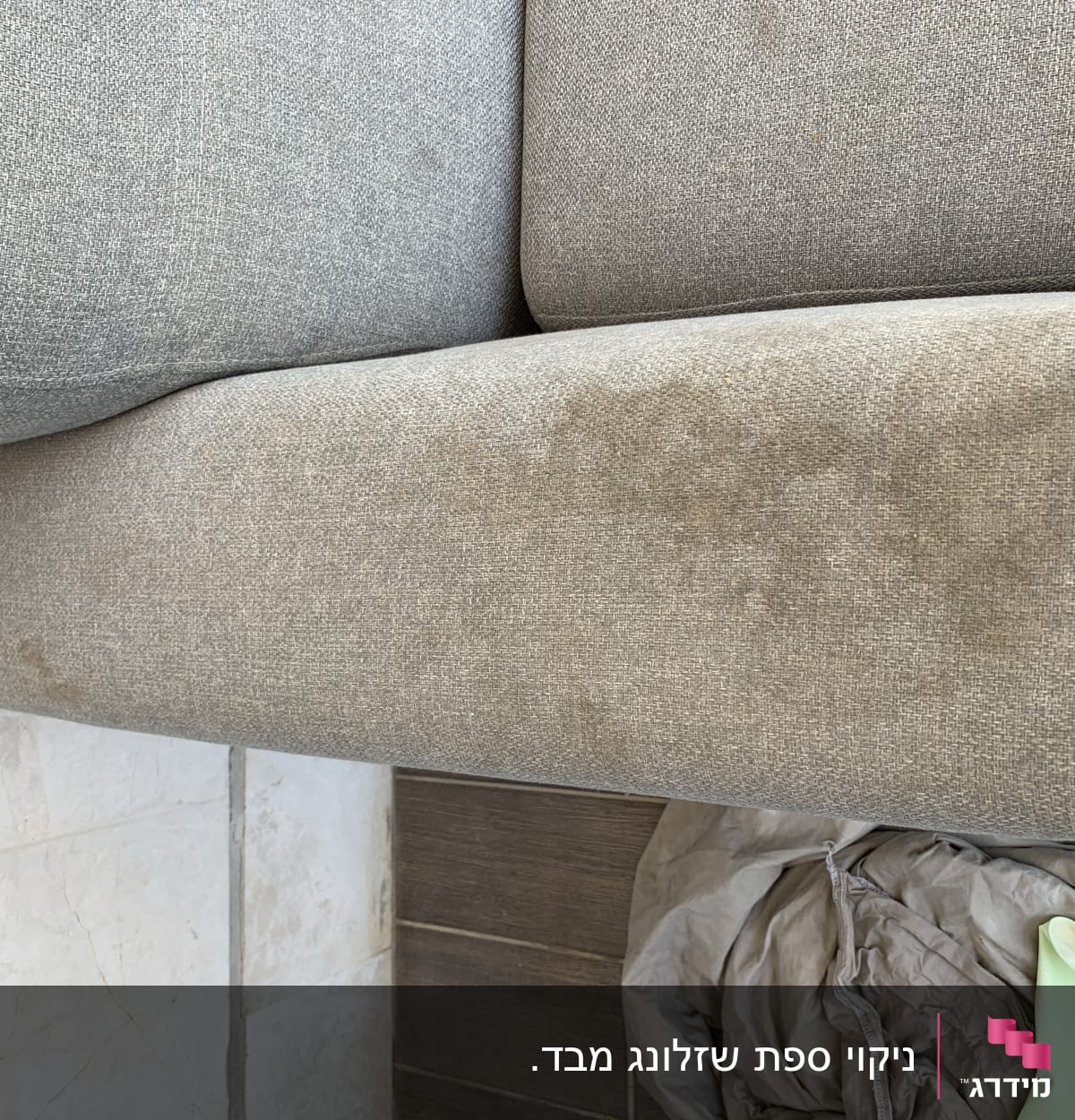 כרית ספה אפורה עם כתמים, כפפה ירוקה ובד על הרצפה